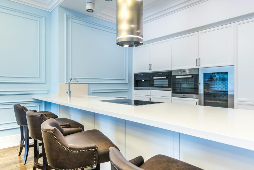 Vibrant blue kitchen with sleek, modern design, featuring stainless steel appliances and ample natural light."